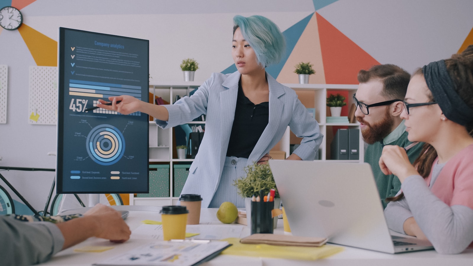 Team member presenting company analytics on screen to colleagues in the office